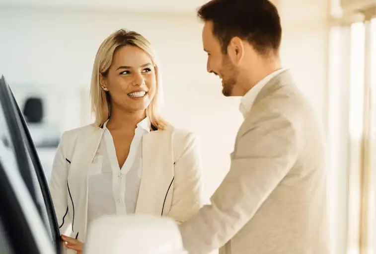 Car salesman shows happy woman car in showroom at Napleton Ford Columbus
